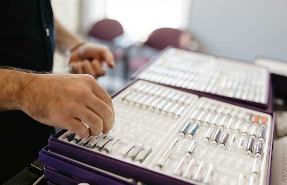 Dr. Dylan Miller selecting vials from a testing kit used for Applied Kinesiology (AK) testing during a patient assessment.