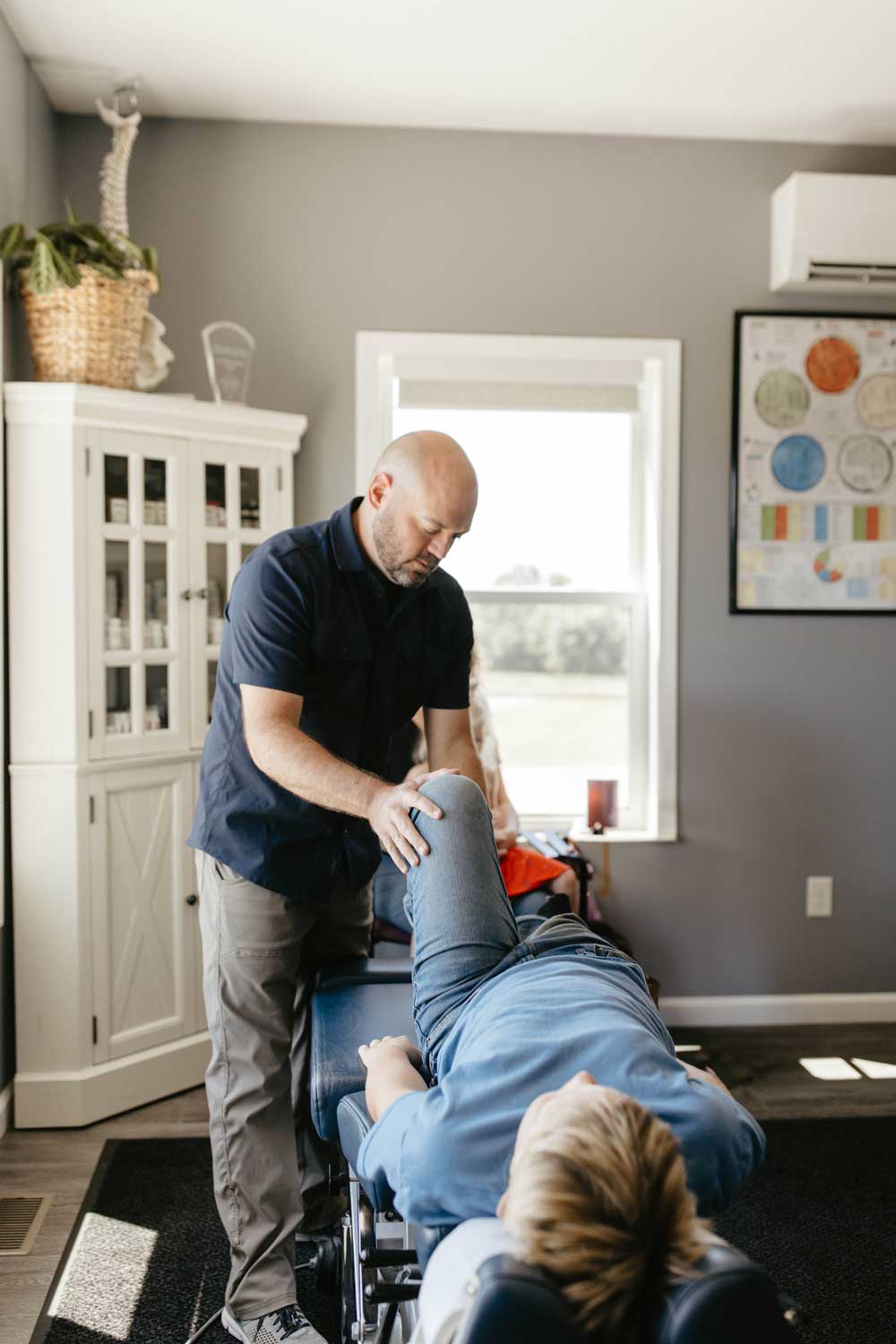 Dr. Dylan Miller performing a chiropractic leg adjustment on a patient to relieve discomfort and enhance mobility.