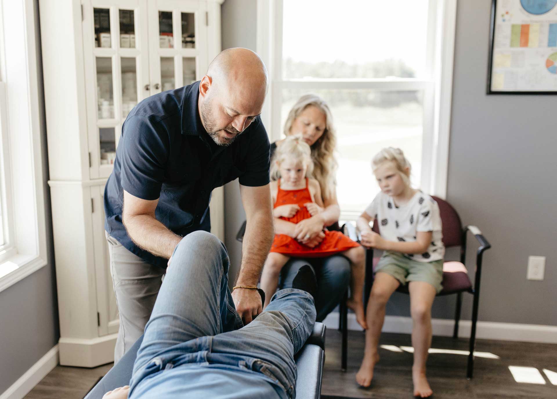 Dr. Miller performing a chiropractic assessment and adjustment on a patient’s knee to alleviate knee pain.