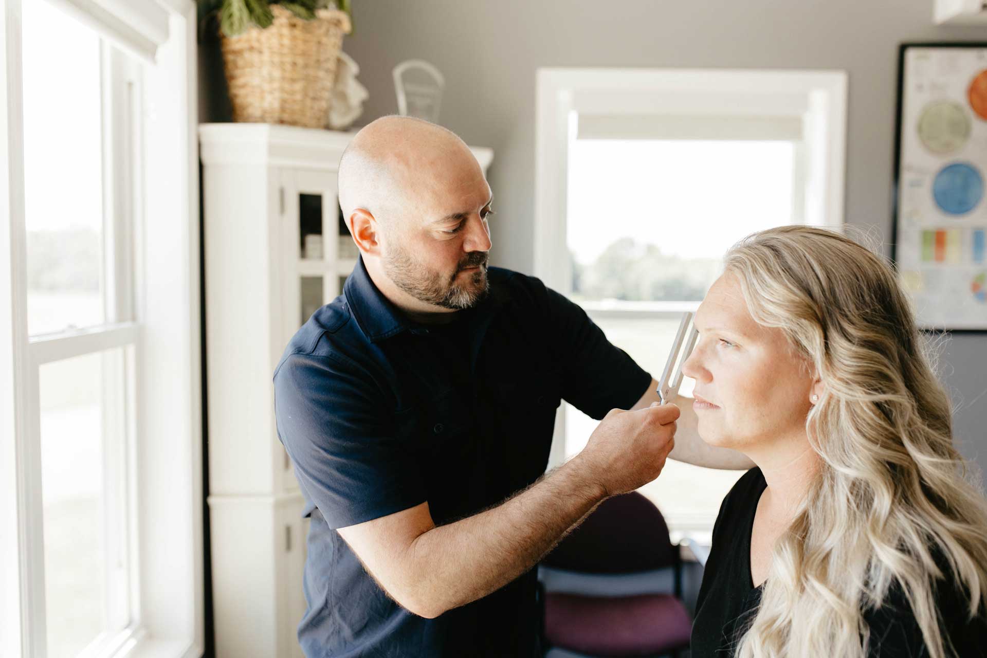 A person receiving a tuning fork therapy session for neck pain relief, showcasing natural healing techniques.