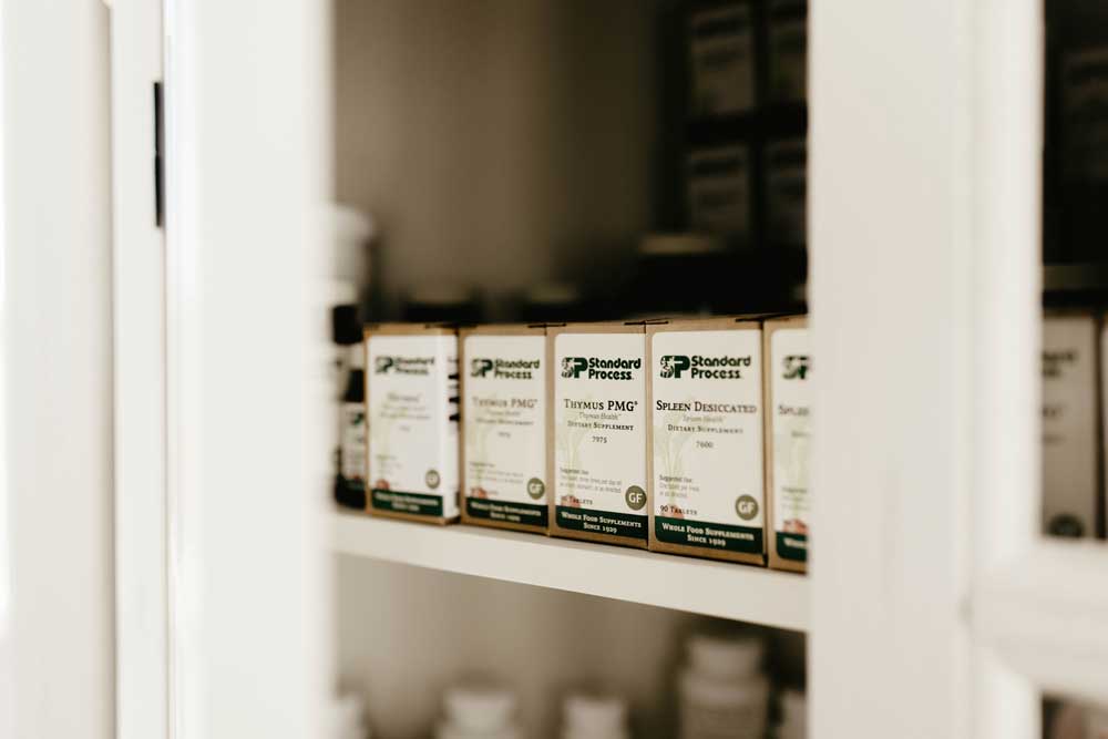 Bottles of Standard Process supplements neatly displayed on a shelf, showcasing natural health products.