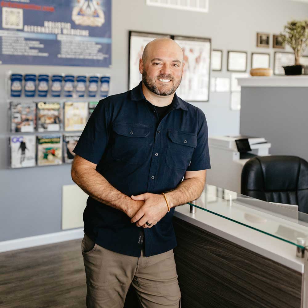 Dr. Dylan Miller greeting patients warmly at the front desk of his clinic, ensuring a welcoming experience.